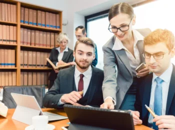 Advogados reunidos em um escritório jurídico analisam através de um notebook os benefícios para antecipação de créditos judiciais com a JusCash.