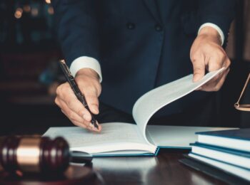 Um profissional da advocacia 4.0 segurando uma caneta e um livro com uma balança da justiça