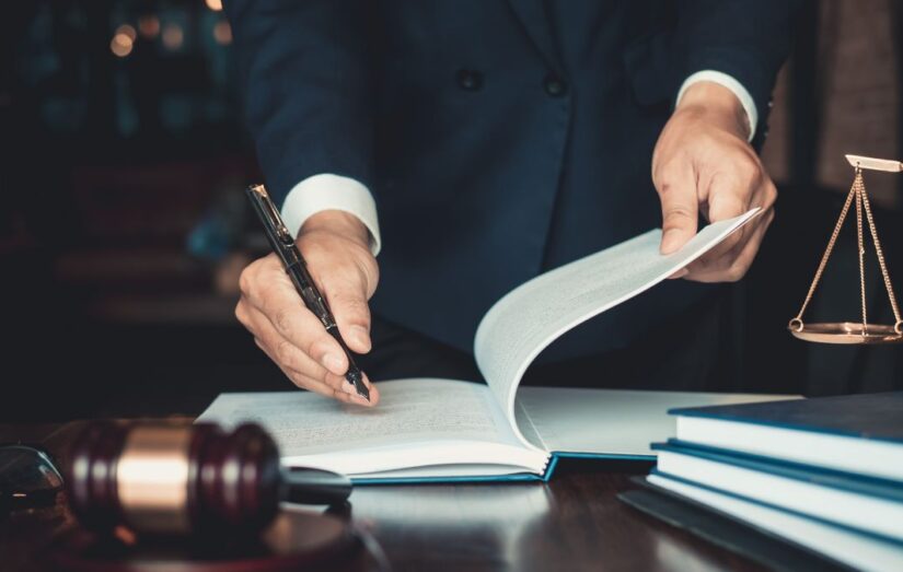 Um profissional da advocacia 4.0 segurando uma caneta e um livro com uma balança da justiça