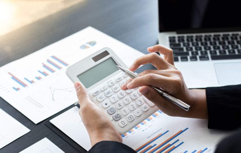 Advogado usando uma calculadora na mesa para calcular a necessidade de capital de giro para seu escritório